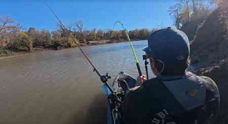 Spencer Bauer hooks into a fish as his Hellcat rod bends sharply on a fast-flowing winter river.